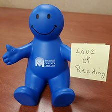 Smiley Guy Cell Phone Holder on desk with post it that says love of reading